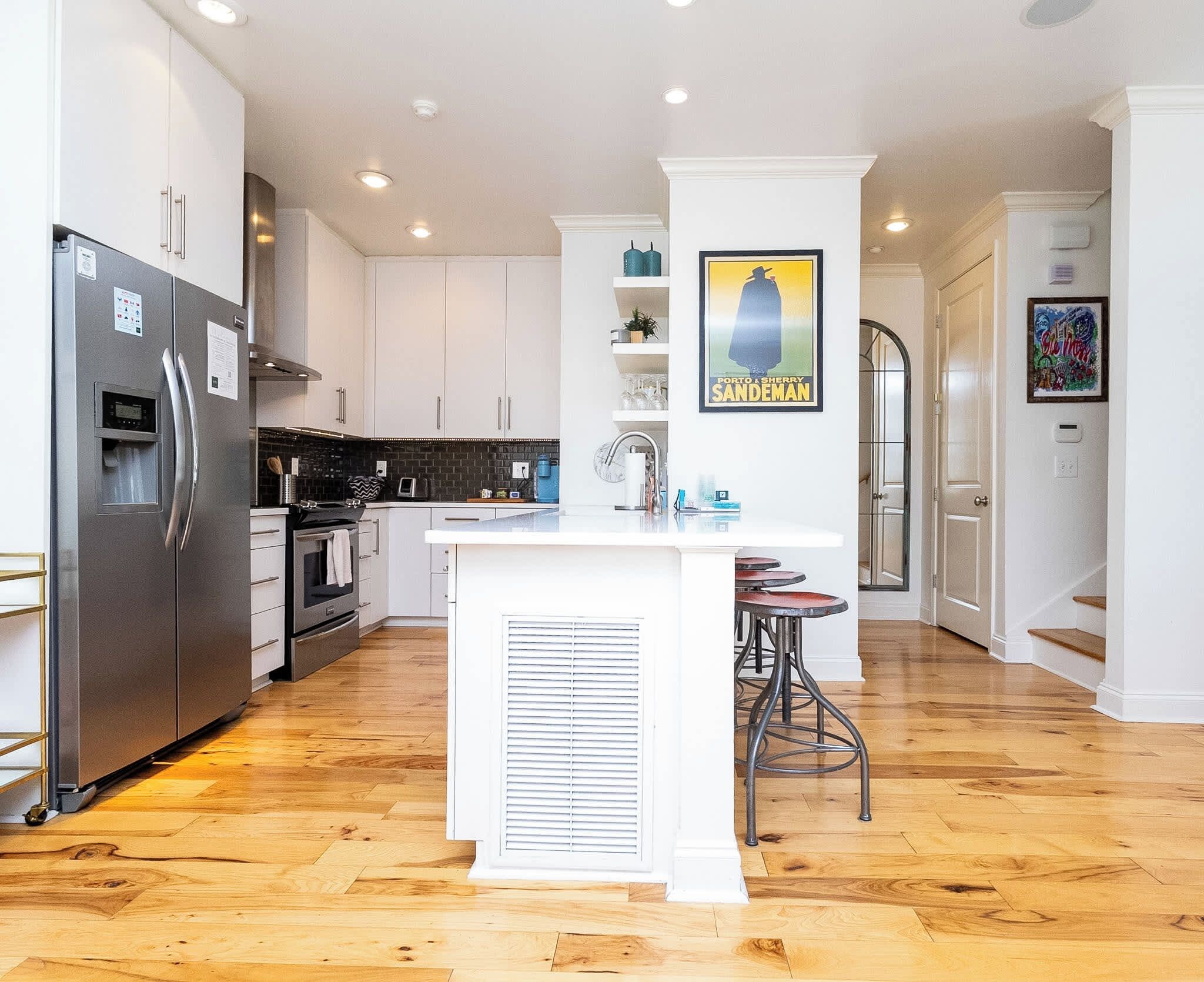A modern kitchen with a central island, stainless steel appliances, and a wooden floor.