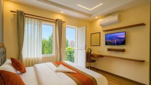 A hotel room with a bed, a desk, a television, and a window with curtains. - Kathmandu Royal Chamber Hotel (Kathmandu)