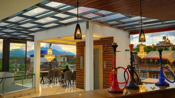 A rooftop terrace with a glass ceiling, outdoor seating, and a view of mountains. - Kathmandu Royal Chamber Hotel (Kathmandu)