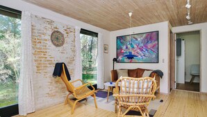 A room with a large window, a painting, and a rattan chair. - 6 Person Holiday Home in Hojby (Hojby)