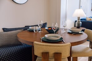 Une table à manger dressée avec des assiettes, des bols et des verres à vin, entourée de chaises rembourrées.