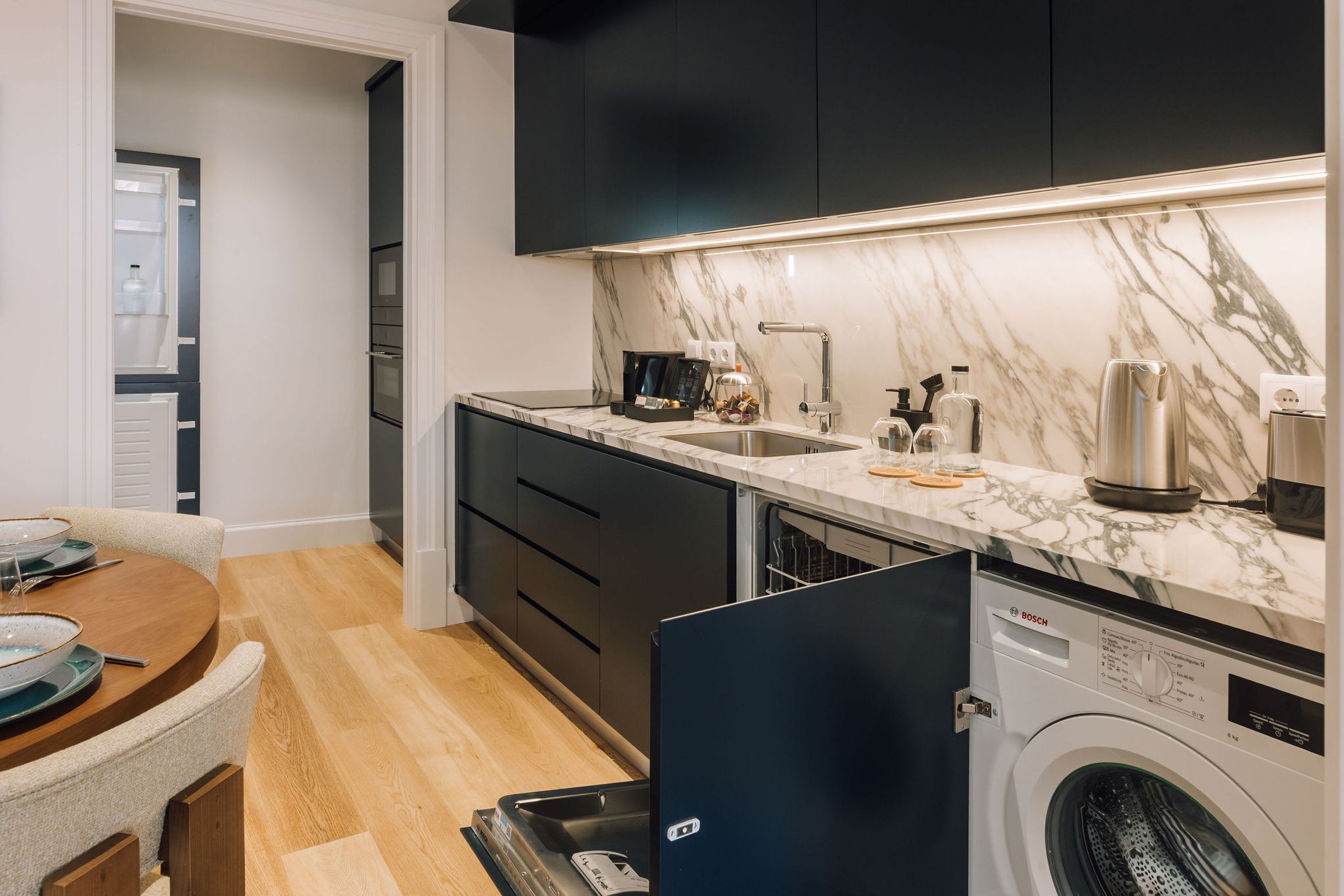 A modern kitchen with a built-in dishwasher, a coffee maker, and a sink.