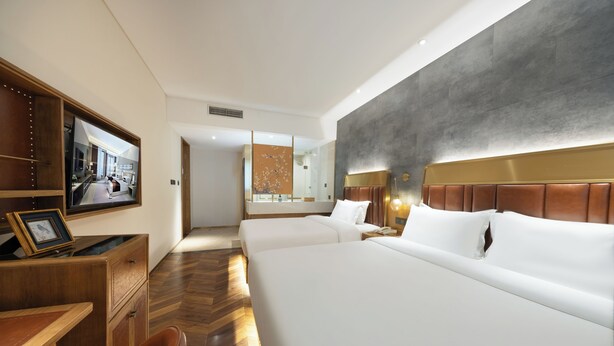 A hotel room with a large bed, a desk with a chair, a television, and a view of the hallway. - Beijing TangFu Chinese Culture Boutique Hotel Sanlitun Embassy Area (Beijing)