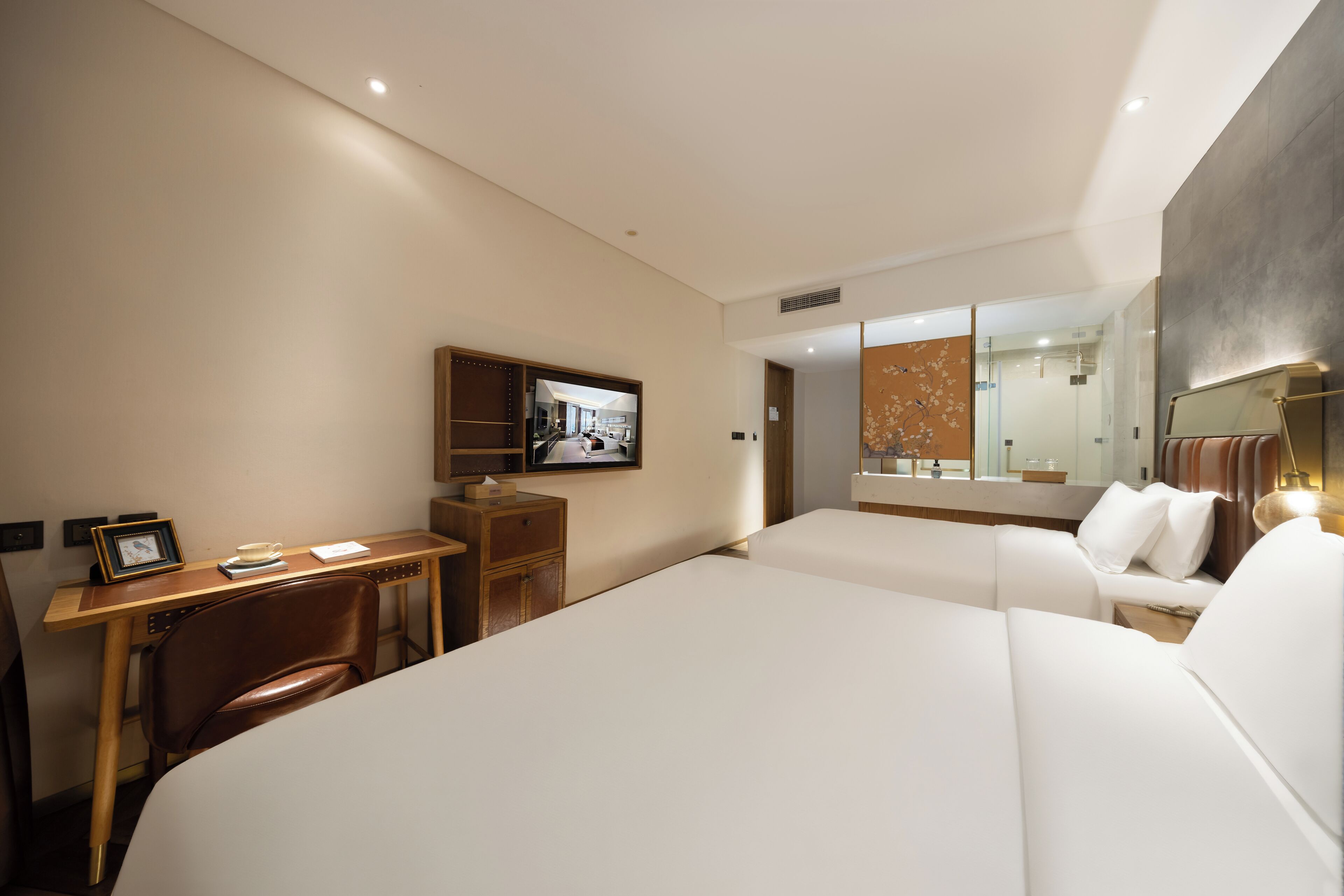 A hotel room with two beds, a desk with a television, and a mirror.