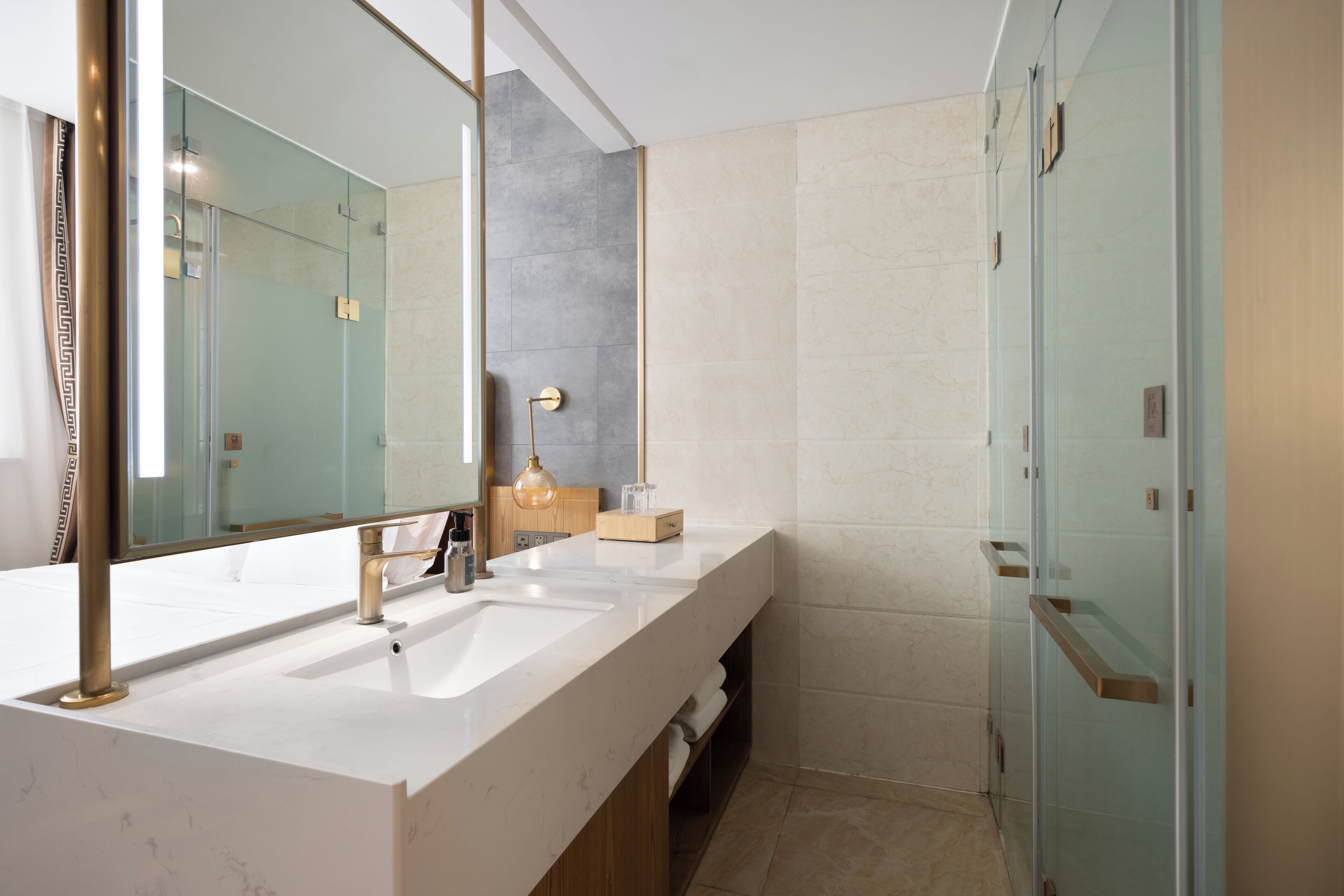 Un baño moderno con un espejo grande, dos lavamanos y una cabina de ducha de vidrio.