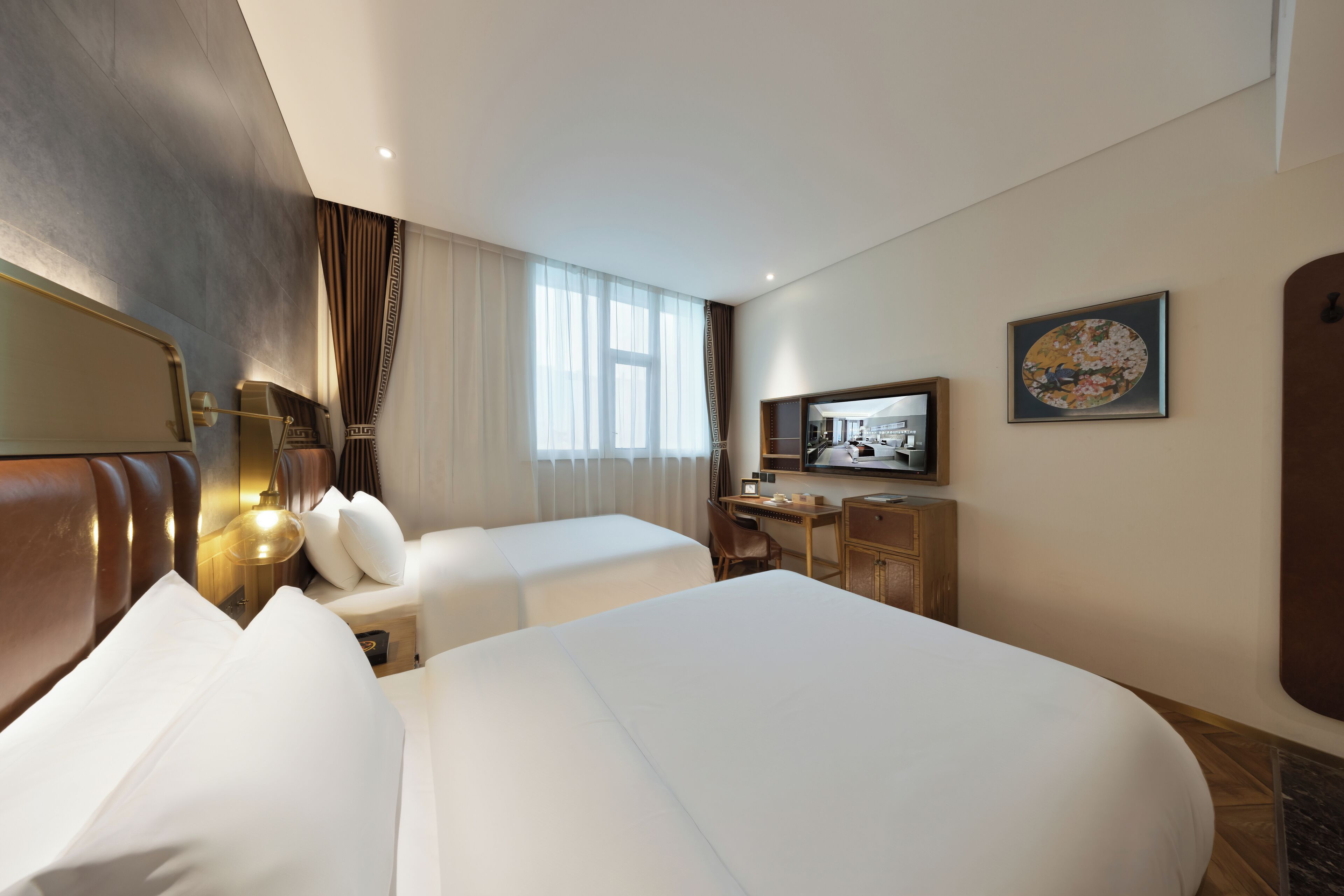 A hotel room with two beds, a desk, a chair, a television, and a painting on the wall.