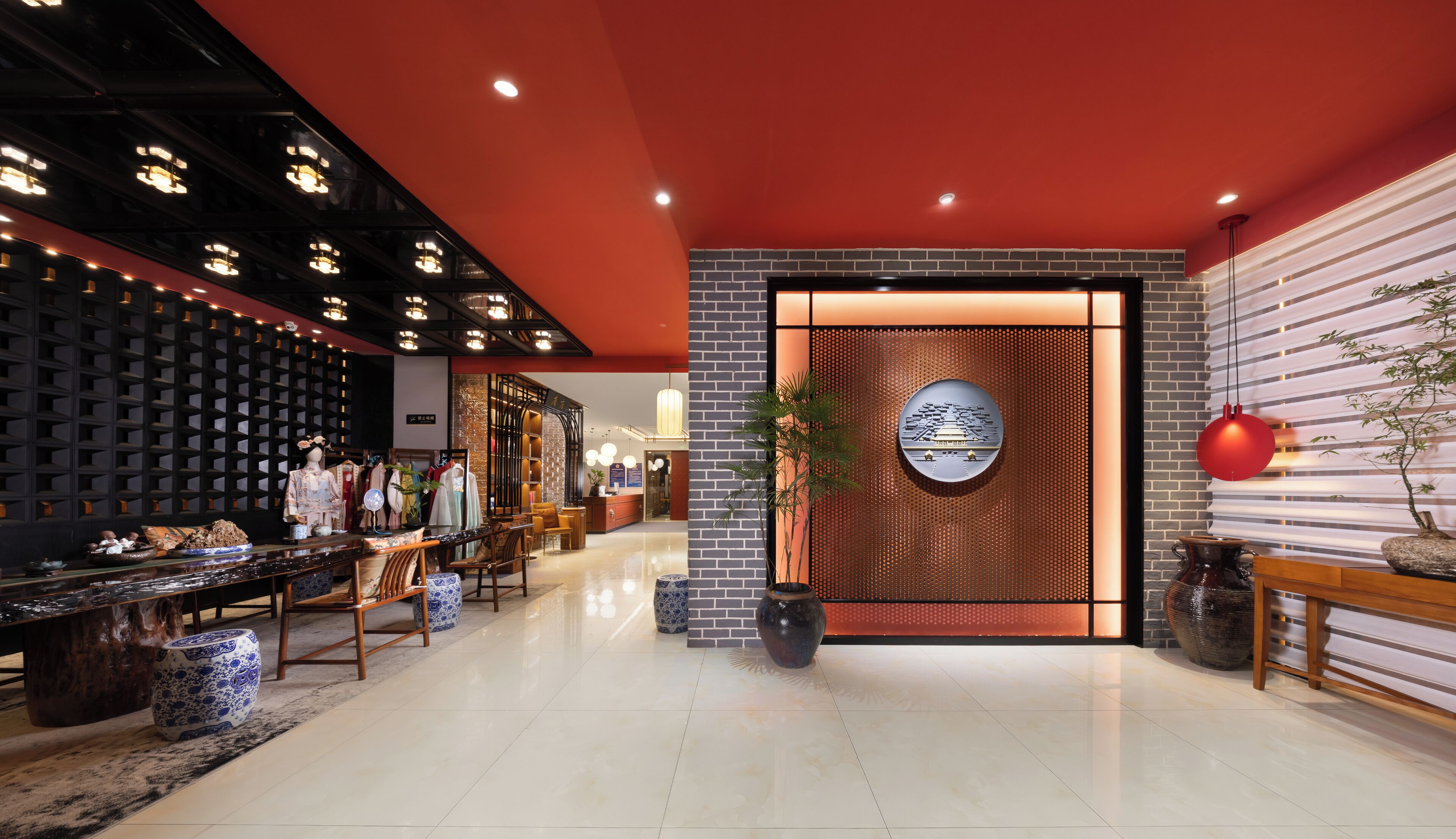 A modern hotel lobby with a brick wall, a reception desk, and a seating area with chairs and tables.