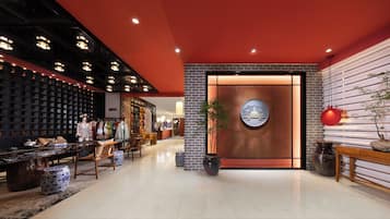 Un moderno vestíbulo de hotel con una pared de ladrillo, un mostrador de recepción y una zona de estar con sillas y mesas.