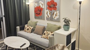 A modern living room with a sofa, a coffee table, a fluffy rug, and a potted plant. - Central Lakeview Apartments (Canberra)