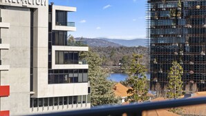 A modern building with a name sign, a view of a lake, and surrounding greenery. - Central Lakeview Apartments (Canberra)