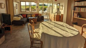 Un salon spacieux comprenant une table à manger, des canapés et une bibliothèque.