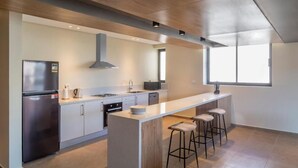 A modern kitchen with a central island, bar stools, and a large window providing natural light.