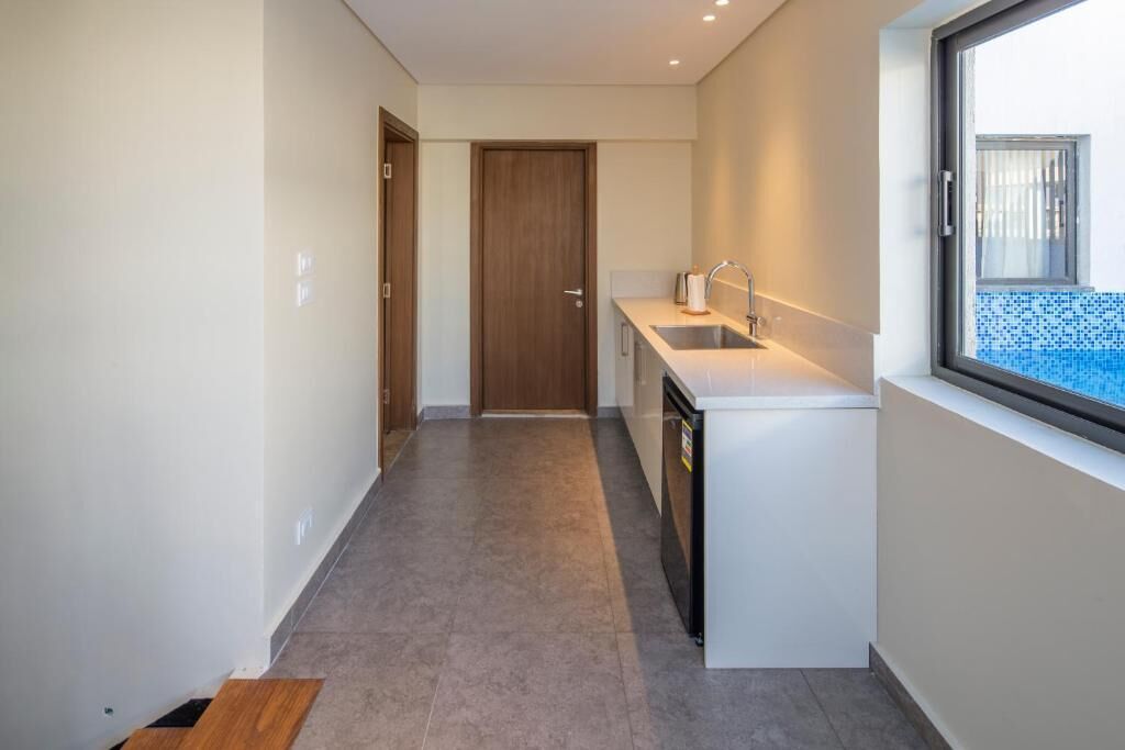 A narrow hallway leading to a kitchen with a window, a sink, and a door.