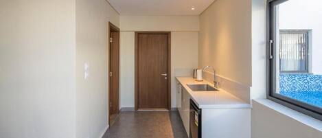A narrow hallway leading to a kitchen with a window, a sink, and a door.