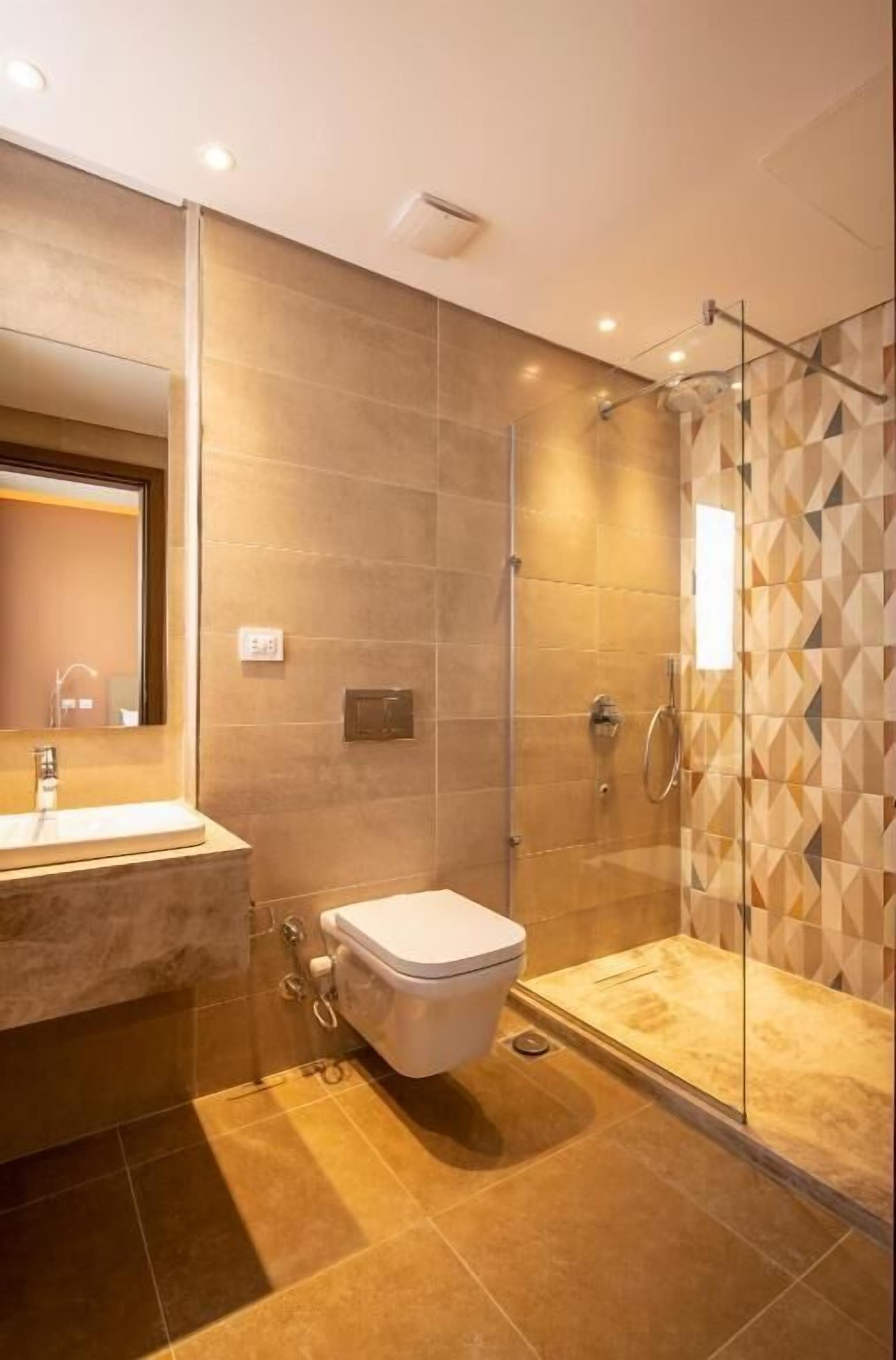 Une salle de bain moderne avec une douche à parois de verre, des toilettes blanches et un lavabo en marbre.