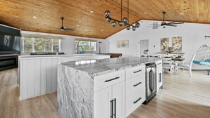 A spacious kitchen with a large island, white cabinetry, and a wooden ceiling.