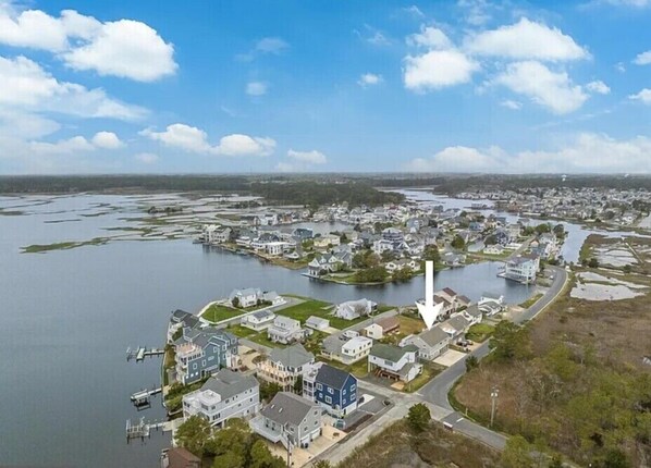 An aerial view of a residential area with houses, a dock, and a large body of water.