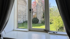Una habitación con ventana que da a una antigua estructura de piedra y follaje otoñal.
