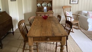 Un comedor con una mesa de madera, sillas, una vitrina y un sofá.