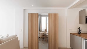 A modern, minimalist living room with a sofa, a wooden wardrobe, and a kitchen area with a countertop and cabinets. - Charming Studio - 2p/ac - Sea View - Antibes (Antibes)