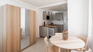 A modern kitchen with grey cabinets, a wooden countertop, and a dining area with a round table and chairs. - Charming Studio - 2p/ac - Sea View - Antibes (Antibes)