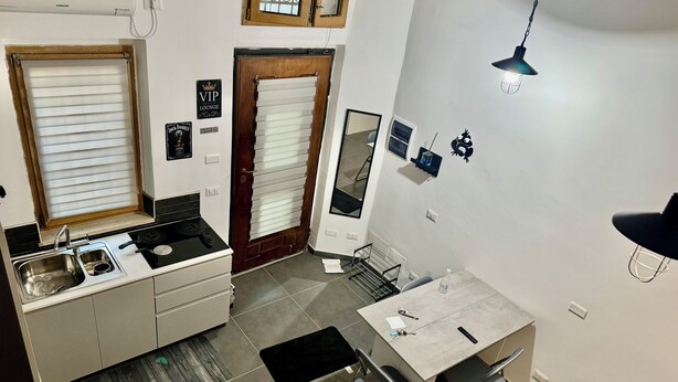 A compact kitchen with a sink, stove, and a dining area with chairs and a table. - The little house of Stellatattoo (Crotone)