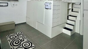 A compact living space with a bunk bed, a flat-screen TV, a small kitchenette, and a staircase. - The little house of Stellatattoo (Crotone)