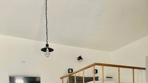 A modern, minimalist room with a bunk bed, a flat-screen TV mounted on the wall, a desk with a chair, and a small staircase. - The little house of Stellatattoo (Crotone)