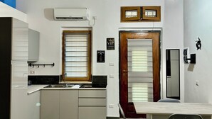 A modern kitchen with white cabinets, a dining area with a table and chairs, and a wooden door with a window. - The little house of Stellatattoo (Crotone)