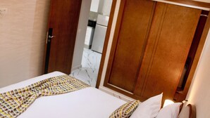 A hotel room with a bed, a wooden wardrobe, and a bathroom visible through an open door.
