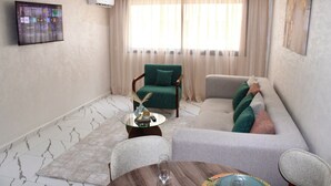A living room with a sofa, armchairs, a coffee table, and a TV mounted on the wall.