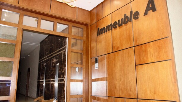 A wooden wall with the text "Immeuble A" and a glass door leading to an interior space.