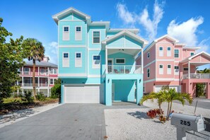 A multi-story residential building with a garage, a mailbox, and a palm tree in the foreground.