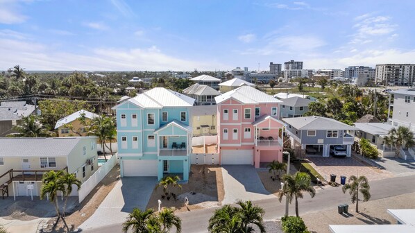 A residential area with colorful houses, a paved driveway, and palm trees.