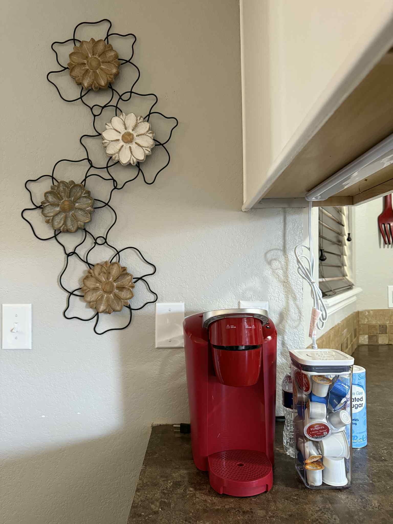 Een keuken met een koffiezetapparaat, een suikerbus en decoratieve wanddecoratie.