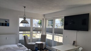 A modern hotel room with a bed, a desk, a chair, and a TV.