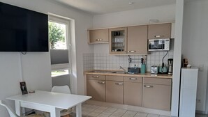 A compact kitchen with a dining area, including a table, chairs, and a microwave.