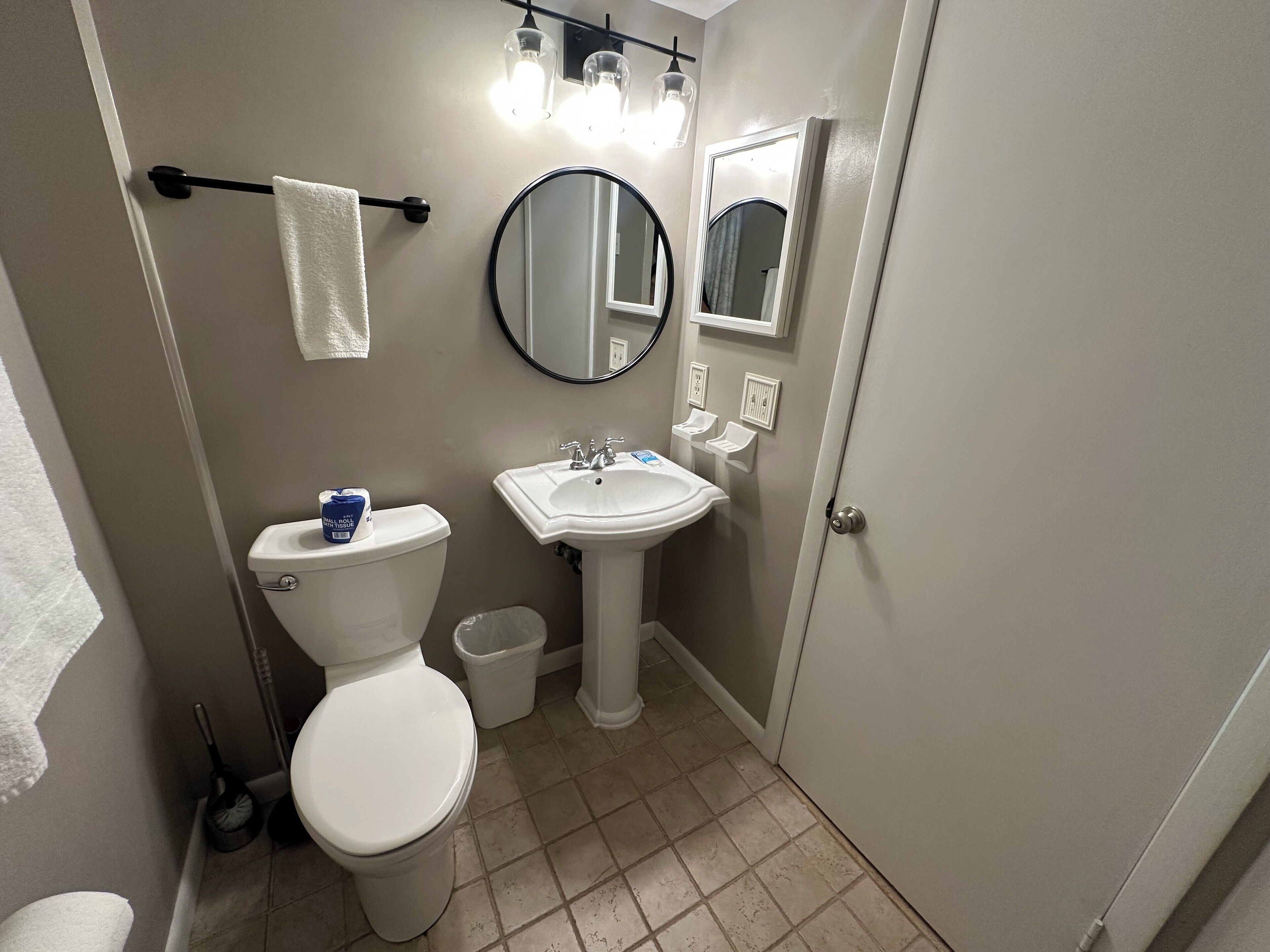 Une salle de bain avec des toilettes, un lavabo et un miroir.