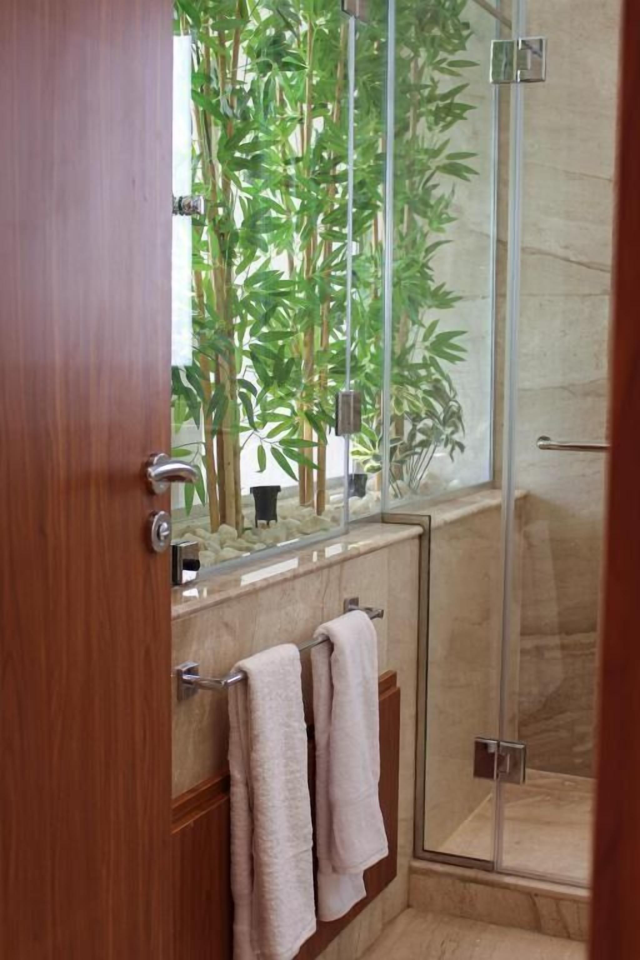Une salle de bain avec une douche à parois de verre, une porte en bois et un porte-serviettes avec deux serviettes.