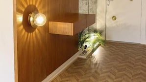 Une pièce avec un mur d’accent en bois, une étagère intégrée, une porte dotée de poignées en laiton et un parquet à motifs en chevrons.