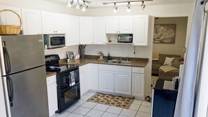 A kitchen with white cabinets, a stainless steel refrigerator, a microwave, and a toaster.