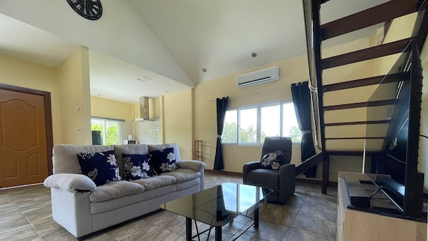 A spacious living room with a sofa, armchair, and coffee table. A staircase is visible in the background. - Quiet 2 bedroom house in Rawai (Rawai)