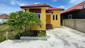 A yellow house with a red-tiled roof, a small porch, and a white picket fence. - Quiet 2 bedroom house in Rawai (Rawai)