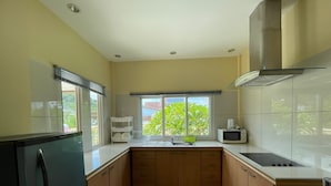 A compact kitchen with a refrigerator, microwave, sink, and wooden cabinets. - Quiet 2 bedroom house in Rawai (Rawai)