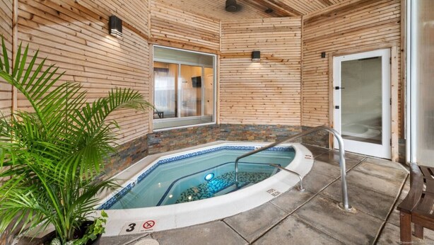 Una piscina interior con paredes de madera y suelo de baldosas, un banco y una planta.