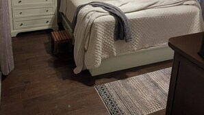 Een slaapkamer met een bed, nachtkastjes, een dressoir, een plafondventilator en een kamerbreed tapijt.