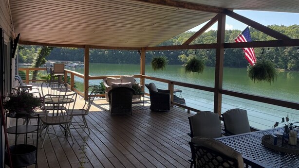 Een overdekt terras met buitenplaatsen en uitzicht op een meer, met een Amerikaanse vlag.