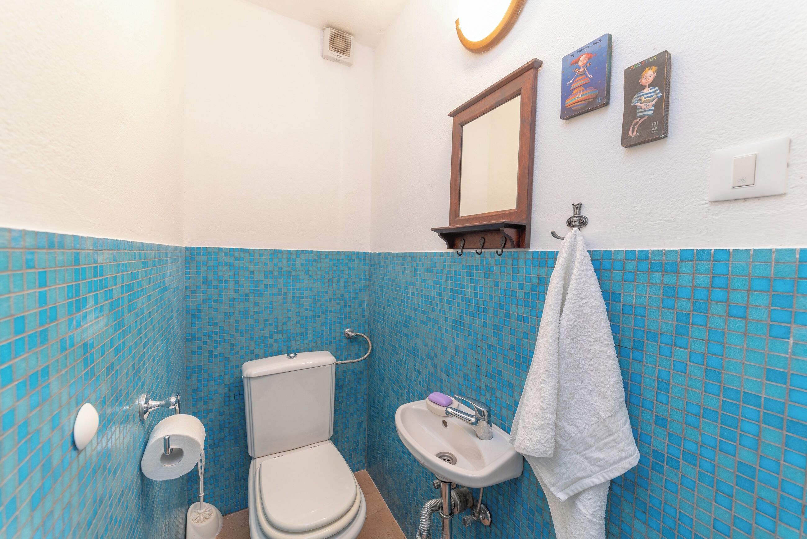 Een badkamer met toilet, wastafel en een handdoek aan een rek.