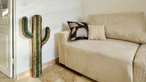 Un salon avec un canapé beige, une décoration à thème de cactus et un sol carrelé.