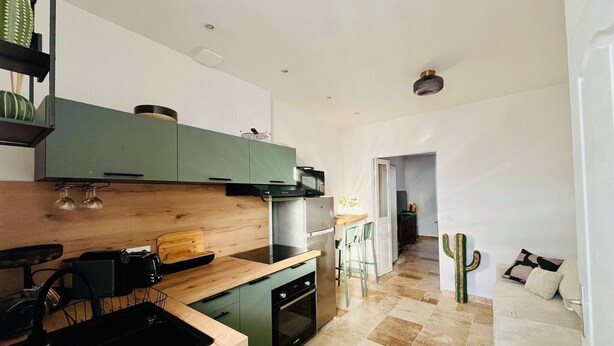 Une cuisine moderne avec des meubles de couleur verte, un plan de travail en bois et un four encastré.